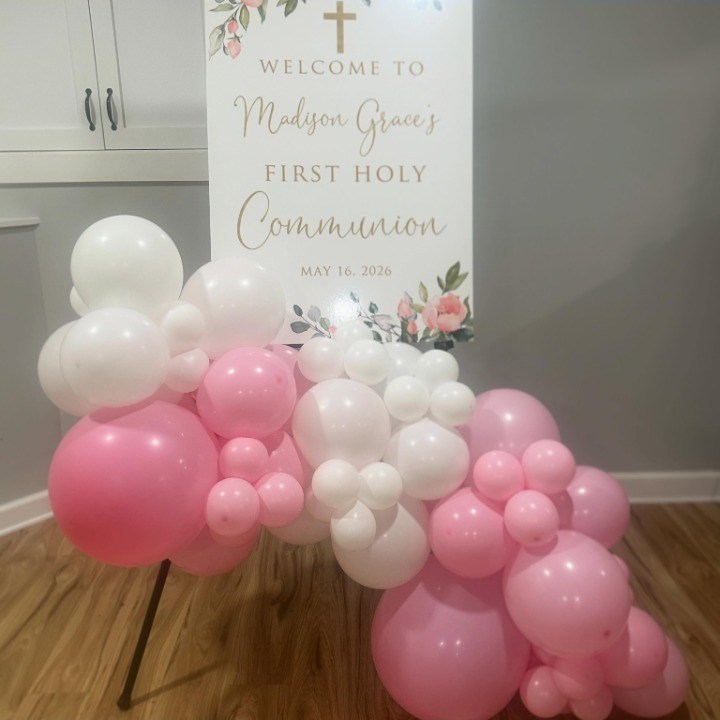 Blush balloon garland beside a first communion sign
